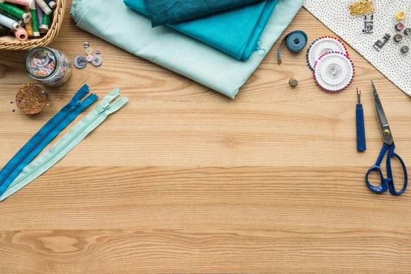 Vue de dessus du lieu de travail de couturière sur la table avec tissu, ciseaux et casiers zip — Photo de stock