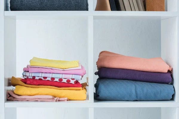 Pile of folded colored fabric on white shelf — Stock Photo
