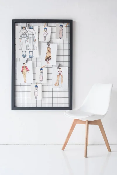 Moldura preta com esboços na parede e na cadeira na sala branca — Fotografia de Stock
