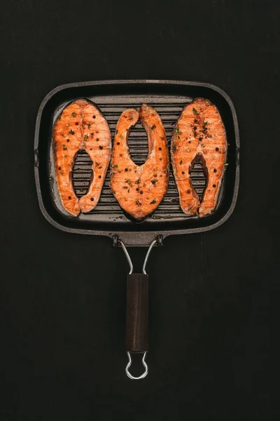Vista superior da grelha com deliciosos bifes de salmão isolados em preto — Fotografia de Stock