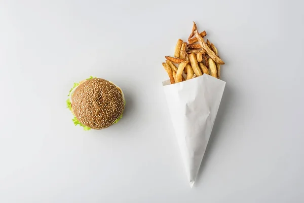 Vista superior de hamburguesa y papas fritas en cono de papel, aislado en blanco - foto de stock