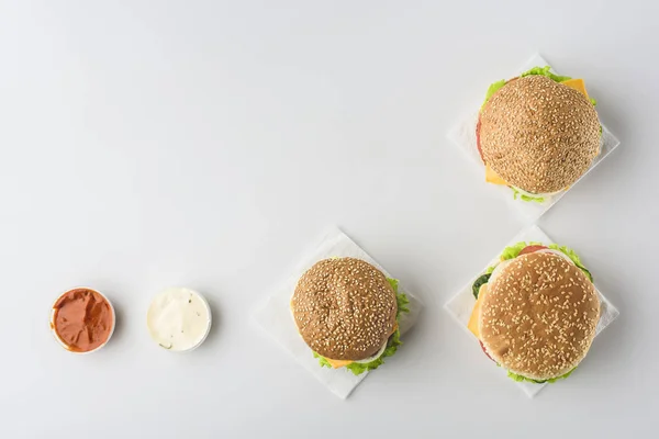 Vista superior de salsas y hamburguesas en servilletas, aisladas en blanco - foto de stock
