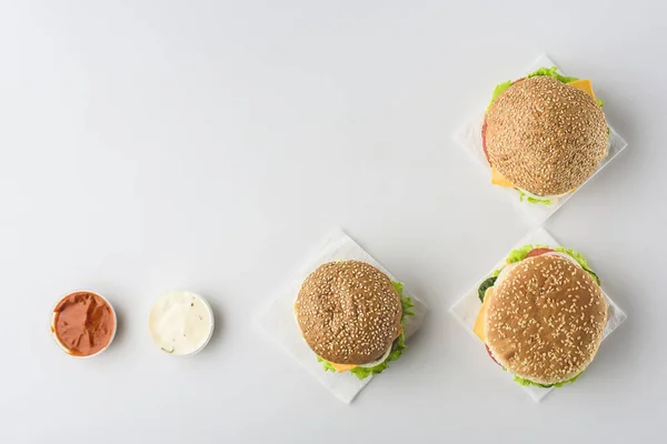 Top view of sauces and hamburgers on napkins, isolated on white — Stock Photo