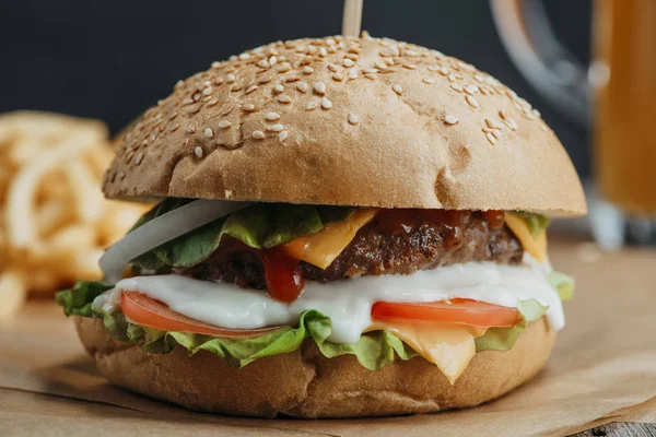 Gros plan des mains féminines avec hamburger maison traditionnelle sur papier cuisson — Photo de stock