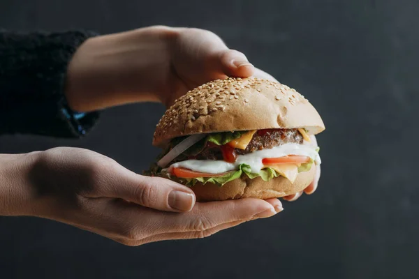 Cropped view of female hands with traditional american homemade burger — Stock Photo