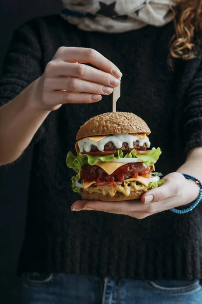 Vue recadrée de femme tenant grand cheeseburger américain traditionnel — Photo de stock