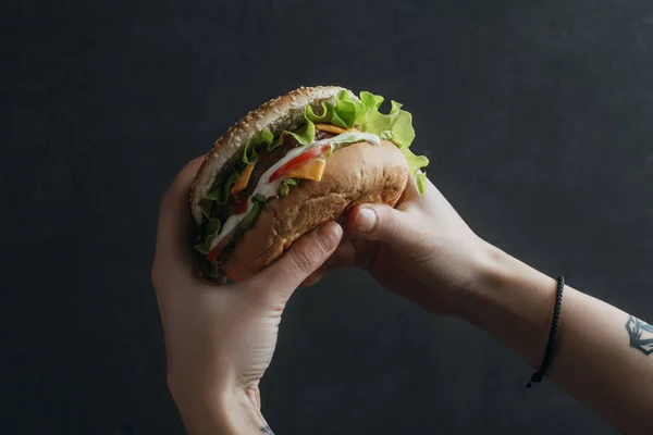 Visão cortada de pessoa comendo cheeseburger saboroso — Fotografia de Stock