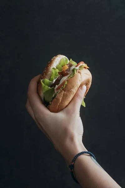 Vista recortada de la persona holdong sabrosa hamburguesa con queso - foto de stock