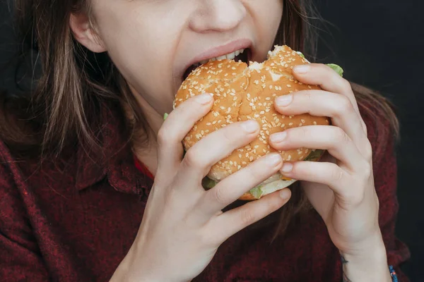 Vue recadrée de fille mordant hamburger savoureux — Photo de stock