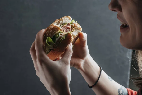 Abgeschnittene Ansicht einer Frau, die leckeren Hamburger isst — Stockfoto