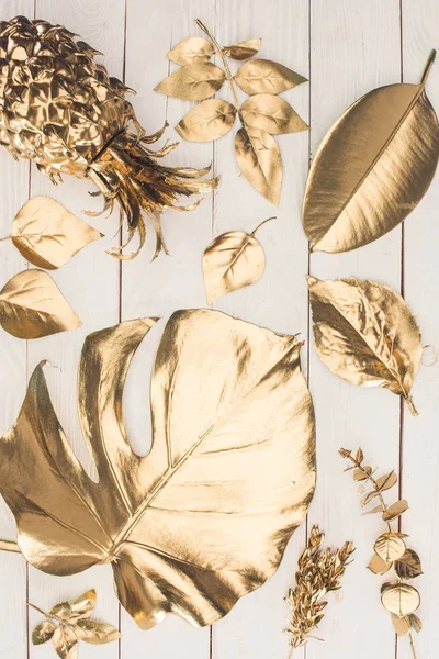 Вид зверху на набір різних золотих листя і ананас на дерев'яній поверхні — стокове фото
