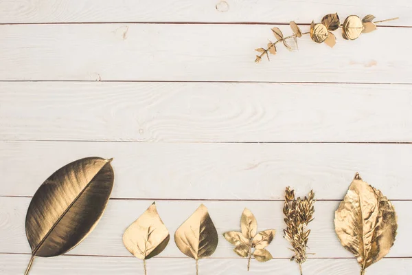 Вид сверху на набор различных золотых листьев на деревянном столе — стоковое фото