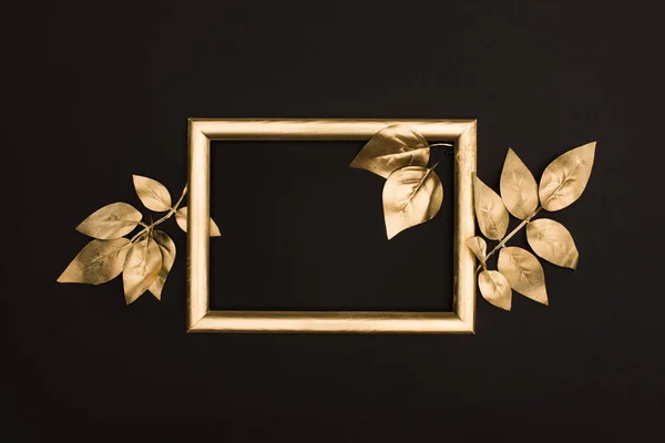 Draufsicht auf goldenen Fotorahmen und Blätter isoliert auf schwarz — Stockfoto