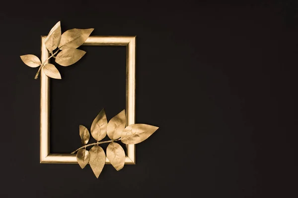 Top view of golden photo frame and leaves isolated on black — Stock Photo