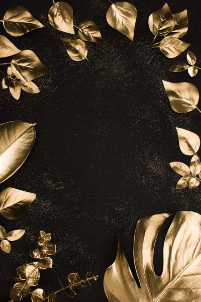 Вид сверху на набор различных золотых листьев на черной поверхности — стоковое фото