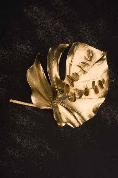 Nahaufnahme von großen goldenen Blättern und Pflanzen auf schwarzer Oberfläche — Stockfoto