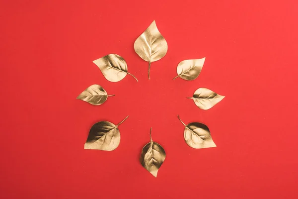 Vue de dessus de disposées en cercle feuilles dorées isolées sur rouge — Photo de stock