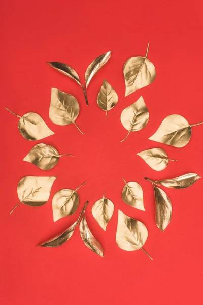 Vue de dessus de disposées en cercle feuilles dorées isolées sur rouge — Photo de stock