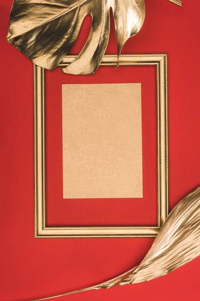 Top view of golden photo frame, leaves and blank paper isolated on red — Stock Photo