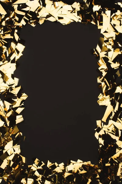 Close up view of sparkling golden confetti isolated on black — Stock Photo