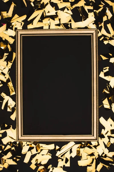 Vista de cerca de confeti dorado y marco de fotos aislado n negro - foto de stock