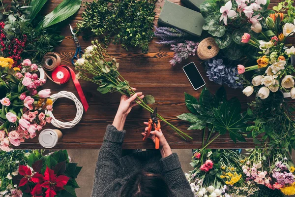 Cropped image of florist cutting stalks of roses with pruner — Stock Photo