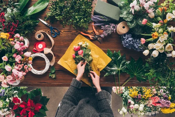 Imagem recortada do buquê de envolvimento florista feminino em papel de embalagem — Fotografia de Stock