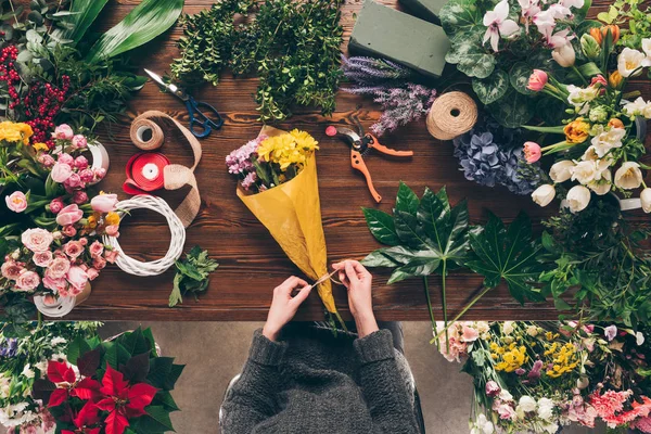 Imagem cortada de florista amarrando fita em buquê na loja de flores — Fotografia de Stock