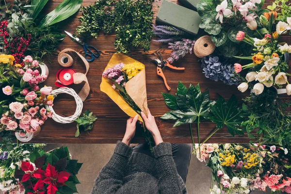 Immagine ritagliata di fiorista che avvolge mazzo in carta da imballaggio in negozio — Foto stock