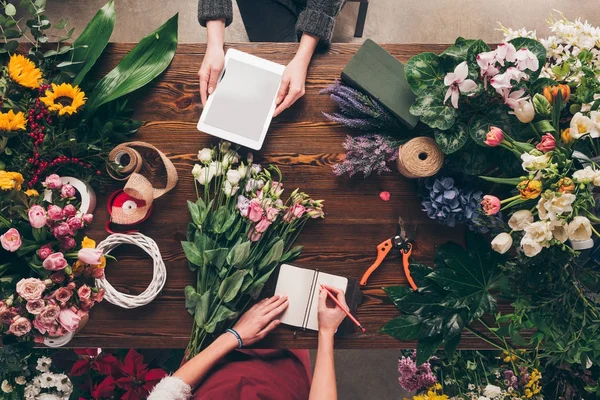 Zugeschnittenes Bild von Floristen mit Tablet und Notizbuch bei der Arbeit — Stockfoto