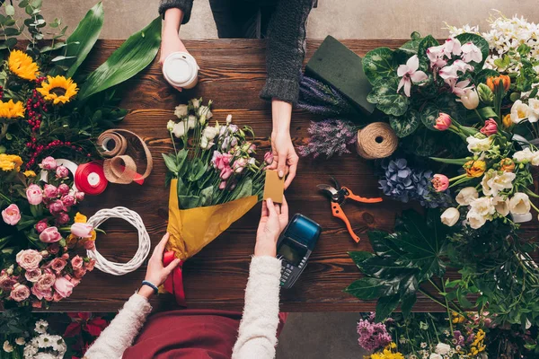 Imagen recortada de cliente dando floristería tarjeta de crédito para pagar ramo - foto de stock