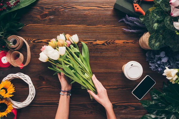 Cropped image of florist making bouquet of tulips — Stock Photo