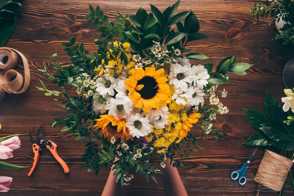 Cropped image of florist putting bouquet of flowers on table — Stock Photo