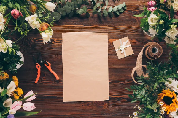 Vista superior de folha de papel e cartão postal entre flores na mesa — Fotografia de Stock