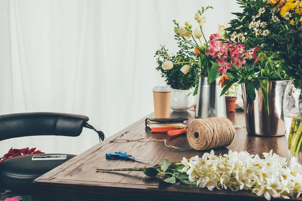 Table de travail fleuriste avec fleurs et outils — Photo de stock