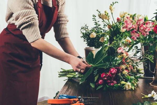 Cropped image of florist adding green leaf to bouquet — Stock Photo
