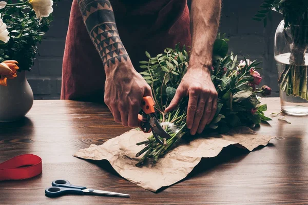 Cropped image of male florist cutting stalks with pruner — Stock Photo