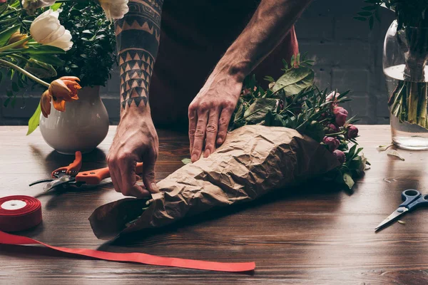 Image recadrée du bouquet d'emballage du fleuriste masculin en papier paquet — Photo de stock