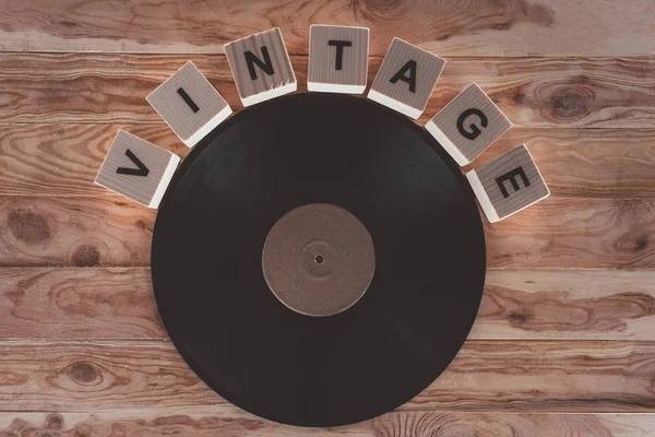 Vista superior de cubos com letras e vinil registro sobre fundo de madeira — Fotografia de Stock