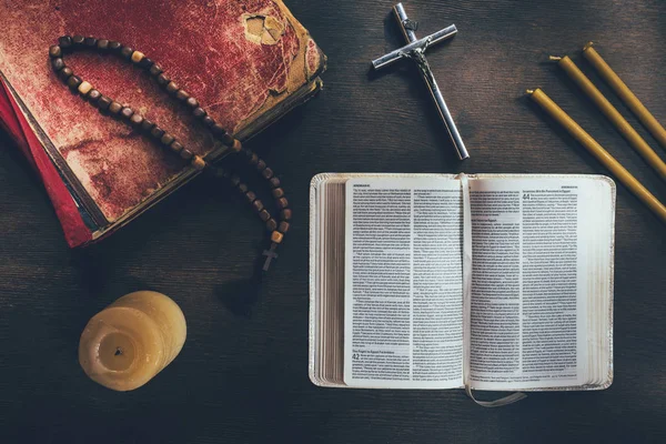 Вид сверху на открытую библию с крестом и четками на столе — стоковое фото