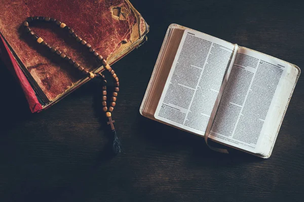 Верхний вид на открытую святую Библию с четками на столе — стоковое фото