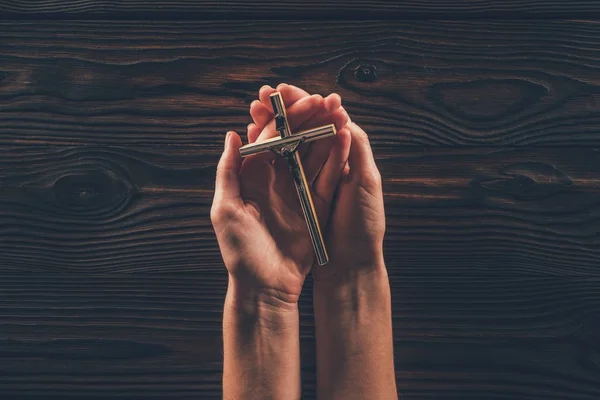 Imagem cortada de mulher segurando cruz em mãos — Fotografia de Stock