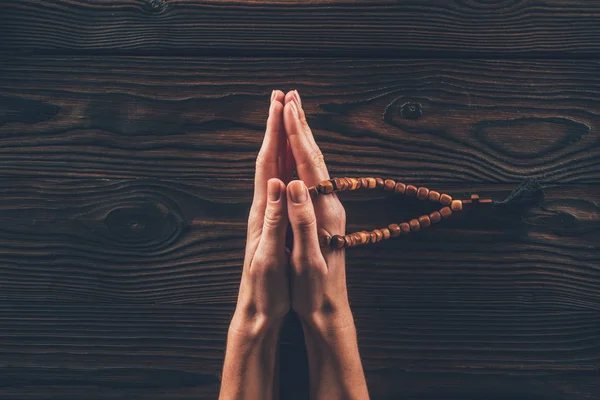 Imagen recortada de la mujer sosteniendo el rosario y rezando en la mesa - foto de stock