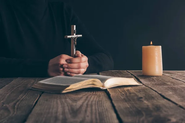 Cropped image of christian sitting with cross in hands — Stock Photo