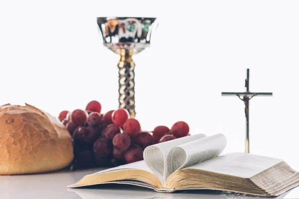 Offene Heilige Bibel mit christlichem Kreuz und Kelch auf dem Tisch, heilige Kommunion — Stockfoto