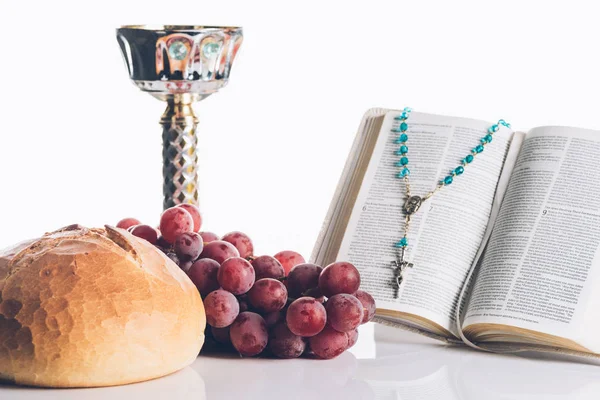 Bible sainte ouverte, nourriture, calice et croix chrétienne sur blanc pour la sainte communion — Photo de stock