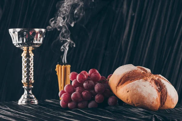 Хліб, виноград, свічки та чашею на темній тканині до святого причастя — стокове фото
