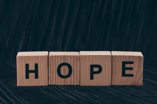 Wooden cubes with word Hope on black table — Stock Photo