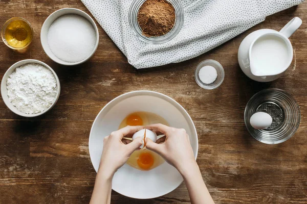 Tiro cortado de mulher quebrando ovos em tigela para pastelaria em mesa de madeira — Fotografia de Stock