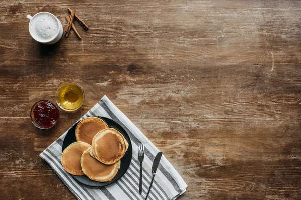 Top view of pancakes on striped napking and coffee cup on wooden table — Stock Photo